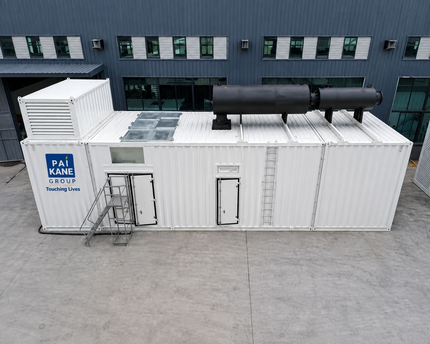 Steel generator enclosure with exhaust silencers and access ladder outside an industrial building.