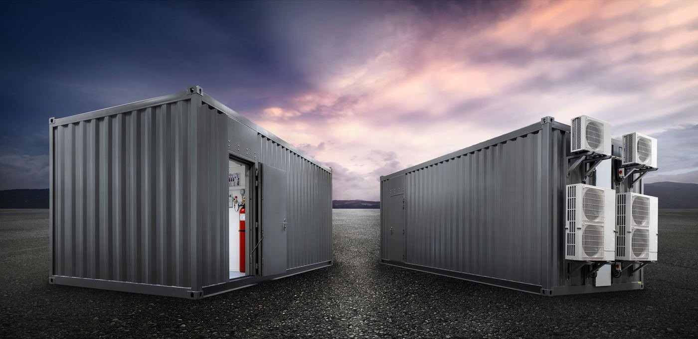 Two Powervault enclosures at dusk — one open showing internal fire suppression cylinder and electrical panel, the other fitted with external HVAC condenser units.